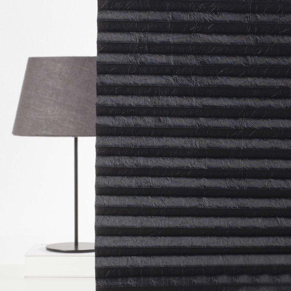 Schwarzes, gefaltetes Plissee in mehreren Lagen steht im Mittelpunkt und entfaltet seine Struktur. Es wird hochwertiges Material verwendet, um Lichtundurchlässigkeit zu gewährleisten.