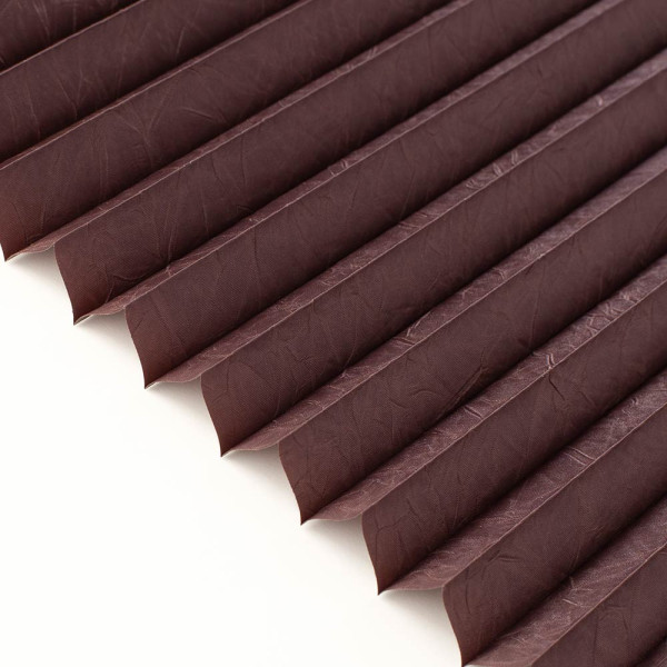 Dunkelbraunes, gefaltetes Plissee mit gleichmäßigen Falten zeigt eine strukturierte Oberfläche. Es steht auf einem hellen Hintergrund und ist bereit zum Einsatz als Sicht- und Sonnenschutz.