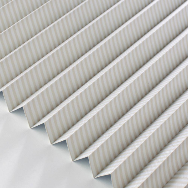 Beige Plissee Zingst 5315 zeigt einen gefalteten Stoff mit feinen, vertikalen Streifen in einem modernen Design. Das Plissee steht elegant angeordnet auf einer hellen Oberfläche.