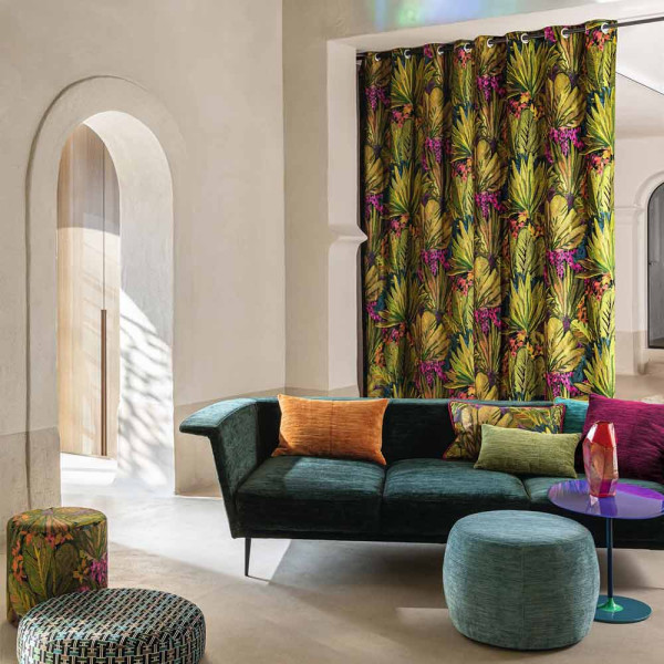 Buntes Stoffmuster mit pflanzlichem Design, featuring grüne und goldene Blätter sowie lila Blumen. Der Stoff liegt leicht gewellt und zeigt komplexe Stickereien.