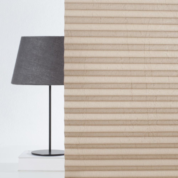 Hellbraunes Plissee mit gefalteter Struktur liegt auf hellen Untergrund. Die Falten sind gleichmäßig und verleihen dem Stoff ein modernes Aussehen. Das Plissee ist blickdicht und maßgefertigt.