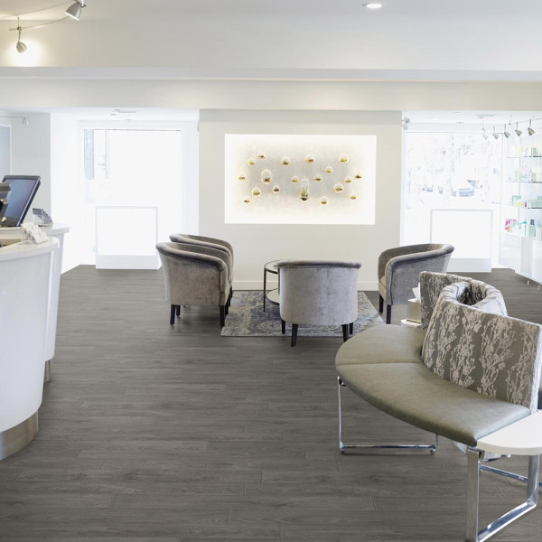 Grauer PVC-Bodenbelag mit Holzstruktur in Landhausdielen-Optik. Die Oberfläche zeigt verschiedene Holzmaserungen und sorgt für einen modernen Look im Raum.