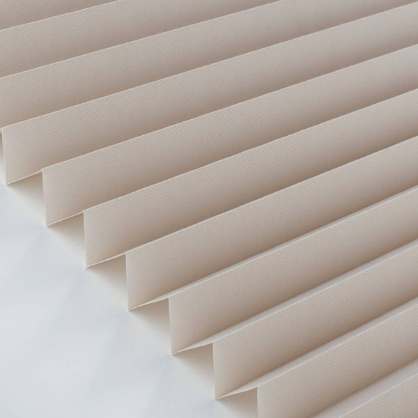 Halbtransparentes Plissee in sanften Naturtönen liegt gefaltet auf einer Oberfläche. Die Stoffstruktur zeigt regelmäßige Falten und wirkt elegant, während die Lichtdurchlässigkeit angedeutet wird.