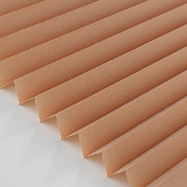 Orangefarbenes Plissee mit gefalteter Struktur liegt flach auf einer Oberfläche. Das Plissee zeigt gleichmäßige Falten und eine sanfte Textur.