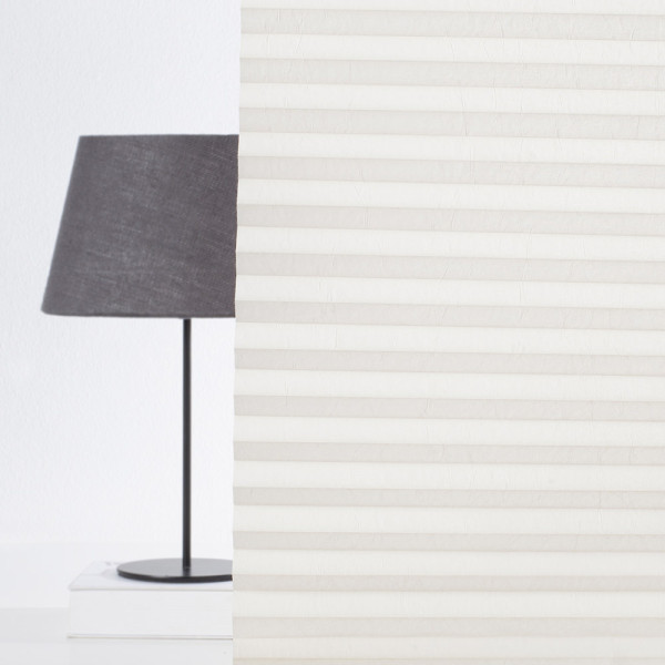 Cremefarbenes Plissee mit strukturierten, gefalteten Lagen liegt flach. Es fungiert als Sichtschutz und wird individuell konfektioniert. Plissee ist für Maßanfertigungen geeignet.