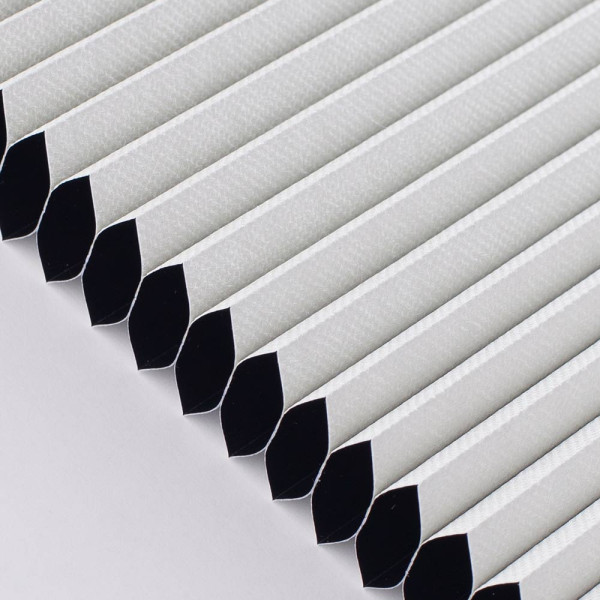 Weißes Wabenplissee Helgoland 3805 mit schwarzem Außenrand liegt flach auf einer Oberfläche. Es ist in gleichmäßige Falten gelegt und dient als verdunkelnder Sonnenschutz.