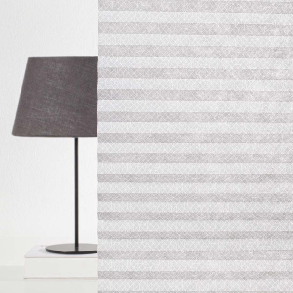 Plissee mit geometrischem, grauem Muster liegt faltig auf einer Oberfläche. Die Struktur zeigt eine gleichmäßige Faltung, die das Licht sanft filtert. Es ist blickdicht und eignet sich für Fensterdekoration.