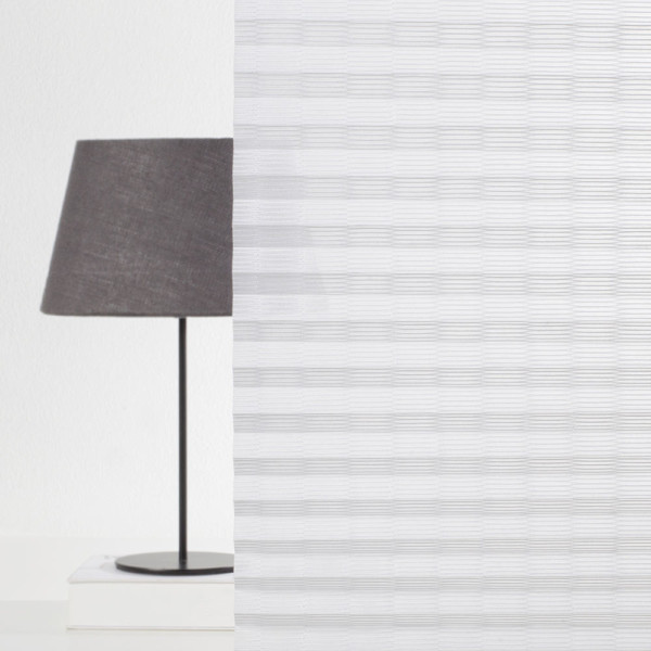 Weißes, gefaltetes Plissee mit transparentem Design liegt auf einer Oberfläche. Die Falten sind gleichmäßig und sorgen für eine elegante Optik. Das Material scheint leicht und lichtdurchlässig zu sein.