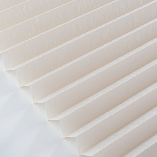Cremefarbenes Plissee mit strukturierten, gefalteten Lagen liegt flach. Es fungiert als Sichtschutz und wird individuell konfektioniert. Plissee ist für Maßanfertigungen geeignet.