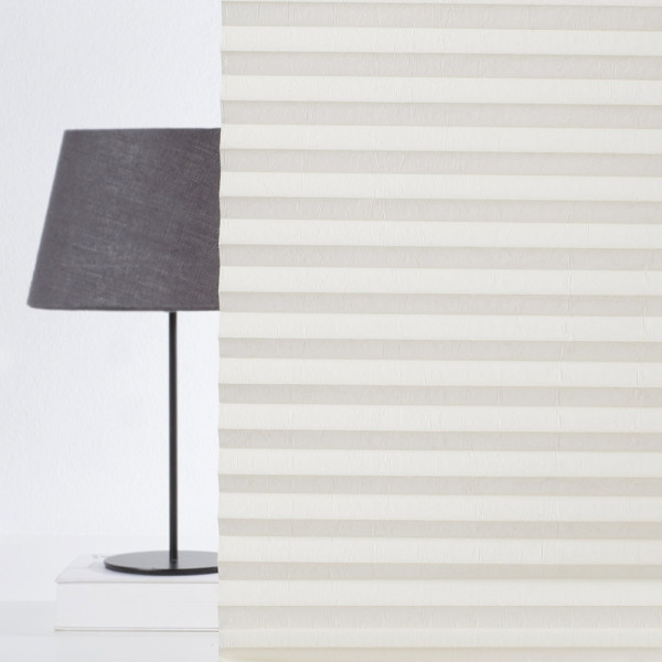 Cremefarbenes Plissee mit gleichmäßigen Falten ist auf einem hellen Hintergrund sichtbar. Es präsentiert sich als Sichtschutz für Fenster und kann nach Maß gefertigt werden.