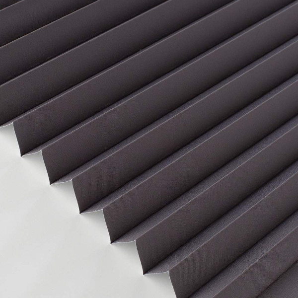 Anthrazitfarbenes Verdunklungplissee mit strukturiertem Faltendesign liegt flach auf einer weißen Oberfläche. Das Material wirkt lichtdicht und eignet sich für individuelle Fensterdekoration.