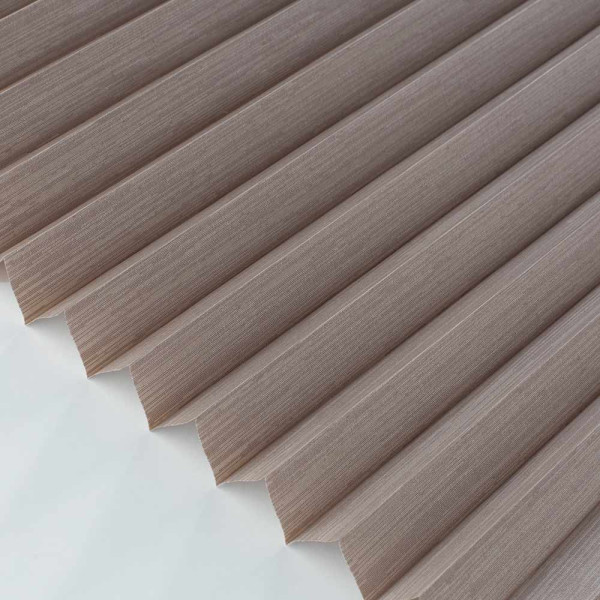 Beige Plissee mit gefaltetem Design liegt auf einer glatten Fläche. Das Material zeigt eine feine, strukturierte Oberfläche, die elegant und modern wirkt.