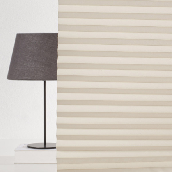Hellbeige Plissee mit gefalteten Lamellen zeichnet sich durch eine halbtransparente Struktur aus. Es bietet eine elegante Lichtregulierung in Wohnräumen. Ideal für maßgeschneiderte Sonnenschutzlösungen.