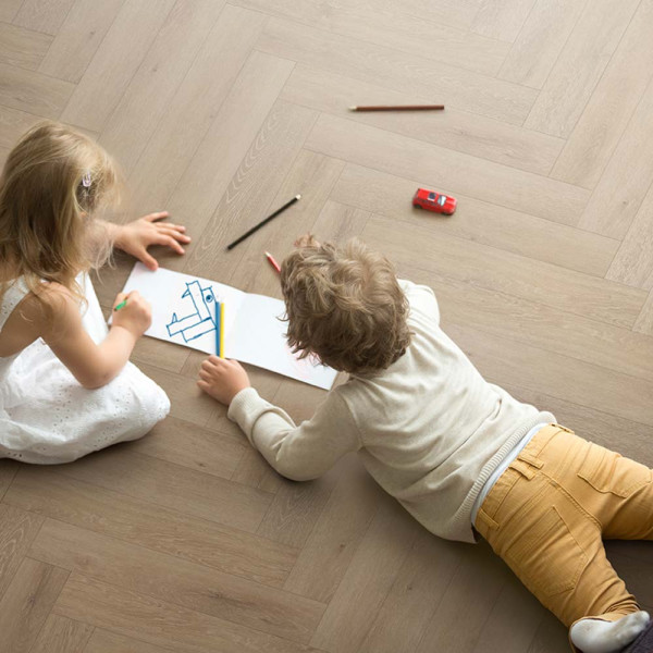 Holzboden mit Fischgrätmuster in hellen Tönen. Die Planken sind in verschiedenen Anordnungen verlegt und vermitteln eine warme Atmosphäre. Ideal für Wohnräume und stilvolle Innenausstattung.