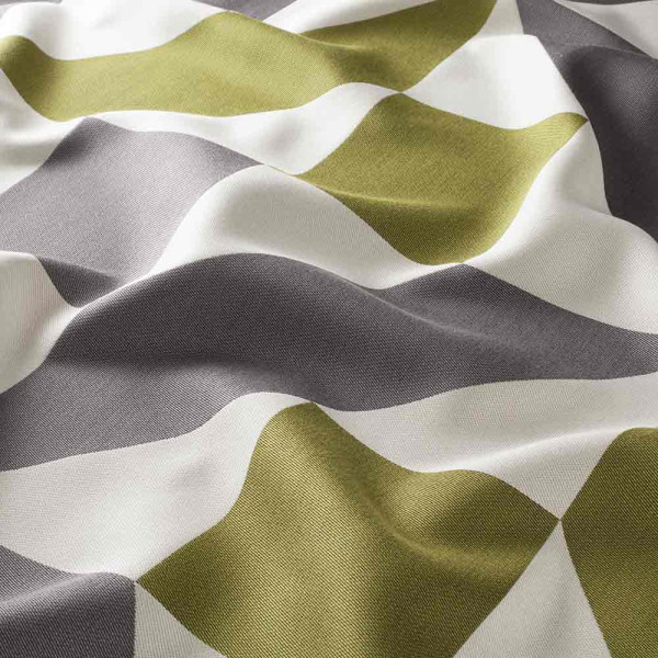 Grüner Vorhangstoff mit Wellenmuster in Grau und Weiß liegt wellig auf einer Oberfläche. Die Struktur und Farbe verleihen dem Stoff eine lebendige Textur.