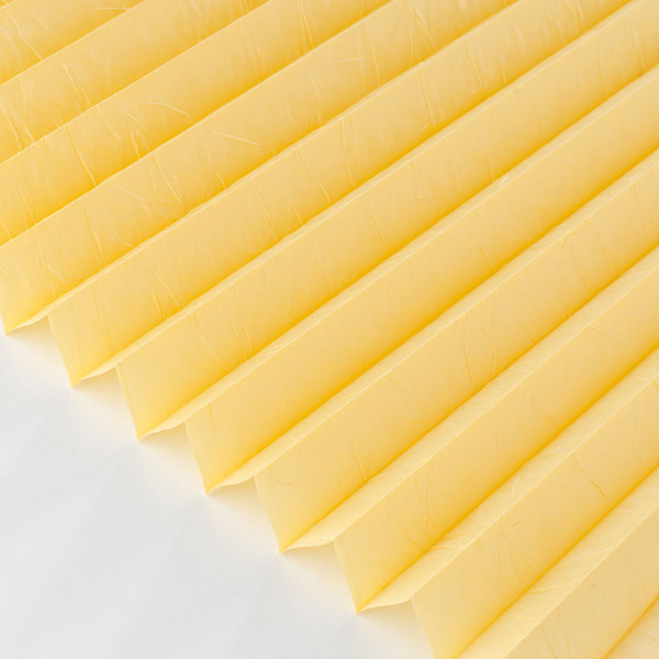 Plissee in gelber Farbe zeigt eine strukturierte, gefaltete Oberfläche. Die Falten sind gleichmäßig angeordnet und reflektieren sanftes Licht. Das Material wirkt blickdicht und hochwertig.