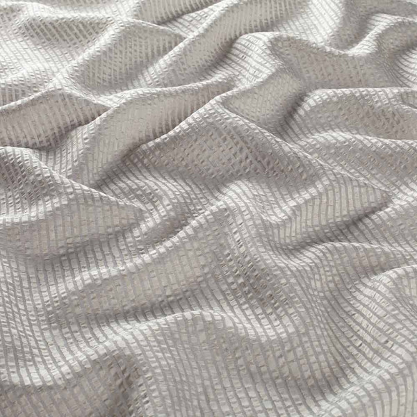 Halbtransparenter Vorhangstoff mit Streifen in hellen Farben liegt gewellt auf einer Oberfläche. Der Stoff zeigt eine feine Textur und ist für Dekorationszwecke geeignet.