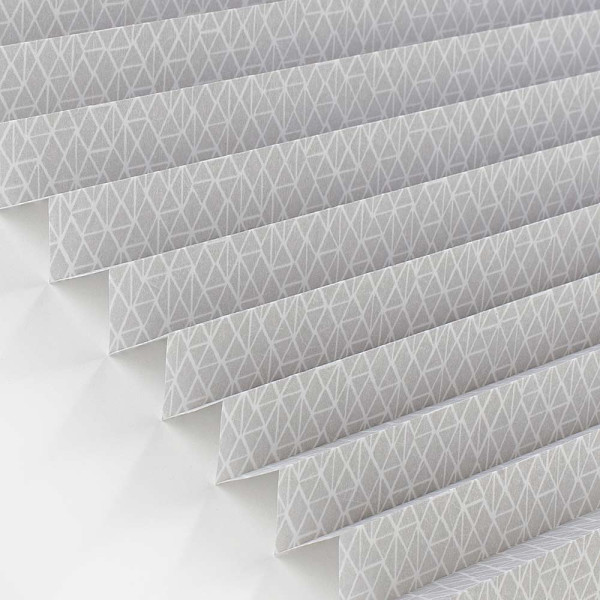 Plissee mit geometrischem, grauem Muster liegt faltig auf einer Oberfläche. Die Struktur zeigt eine gleichmäßige Faltung, die das Licht sanft filtert. Es ist blickdicht und eignet sich für Fensterdekoration.