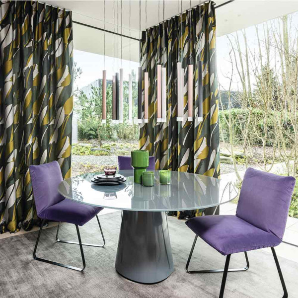 Bunte, gemusterte Textilien zeigen eine Kombination aus Gelb, Grün, Schwarz und Grau in geschwungenen, dynamischen Linien. Der Stoff hat eine strukturierte Oberfläche mit einem modernen Design.