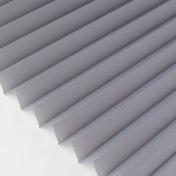 Grau gefaltetes Plissee mit strukturierter Oberfläche liegt auf einer weißen Fläche. Es hat gleichmäßige Falten und bietet halbtransparente Lichtfilterung.