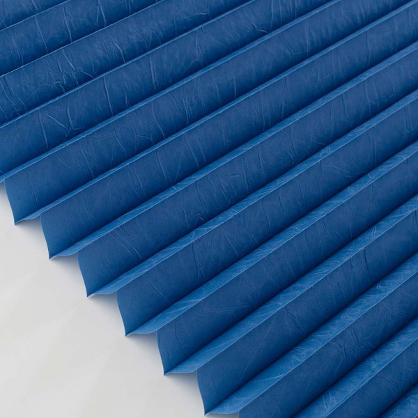 Blaue Plissees mit gefalteten Lamellen liegen ordentlich nebeneinander. Sie sind aus einem hochwertigen Material gefertigt und bieten Sichtschutz, ideal für Fensterdekorationen.