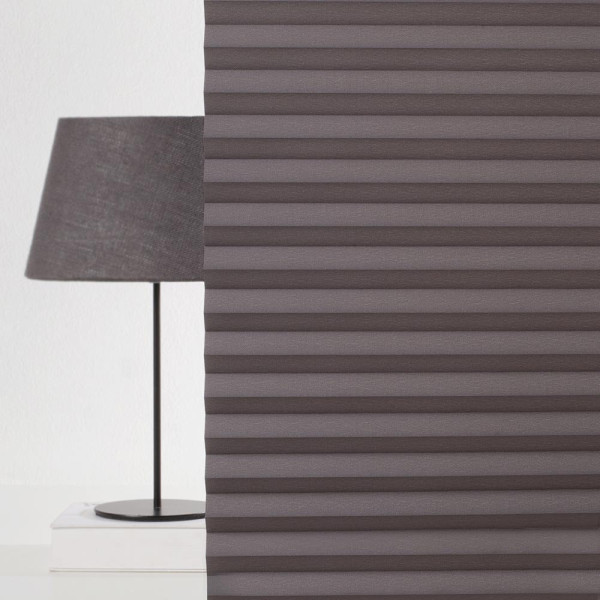 Dunkelgraues Plissee mit einer gefalteten Struktur zeigt die Oberflächenbeschaffenheit der Stoffe. Es steht bereit, um als Sichtschutz eingesetzt zu werden.