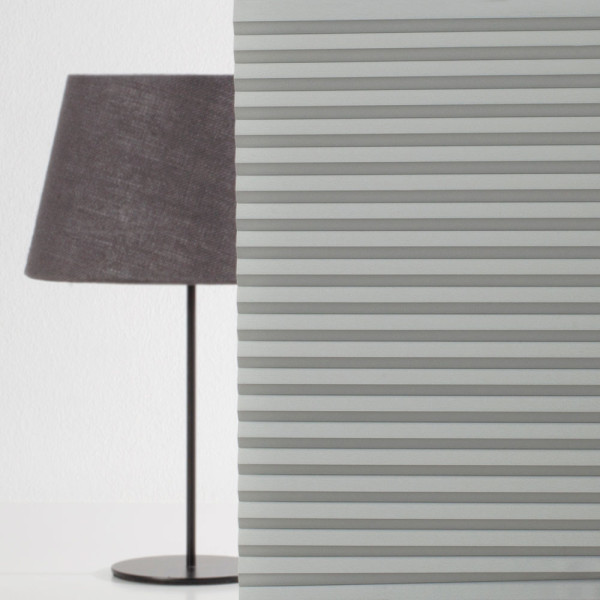 Grau gefaltete Wabenplissees sind in gleichmäßigen Abständen angeordnet. Die Struktur zeigt die Falten und das hochwertige Material, das in maßgeschneiderte Produkte eingesetzt wird.