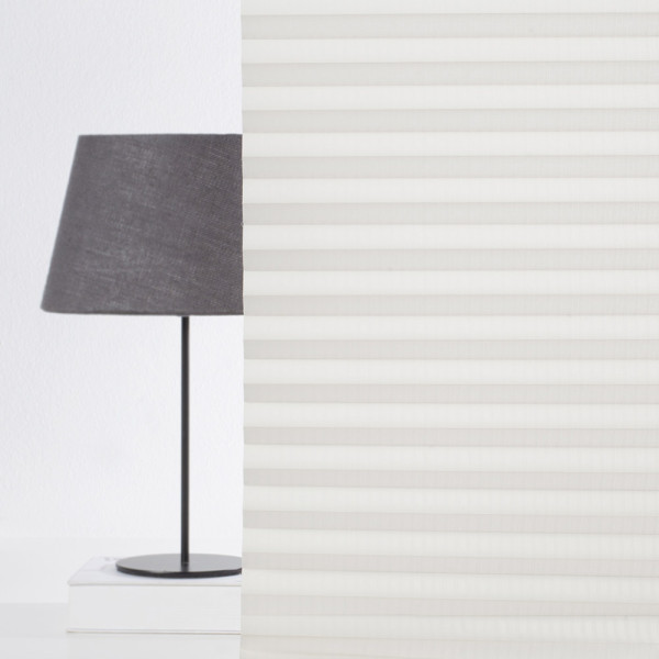 Plissee in Cremefarbe zeigt eine gefaltete Struktur mit gleichmäßigen Falten. Es steht auf einem weißen Hintergrund und verdeutlicht die blickdichte Qualität des Materials.