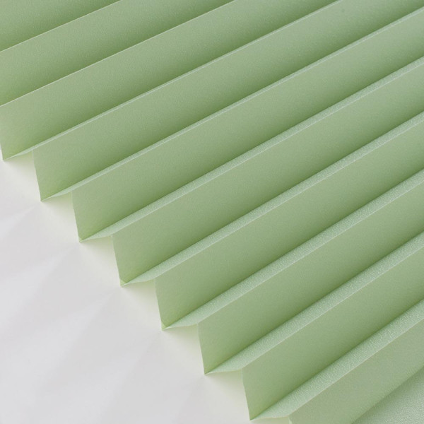 Hellgrünes Plissee mit gefalteter Struktur liegt auf weißem Hintergrund. Es zeigt gleichmäßige Falten, die ein modernes und elegantes Design vermitteln.