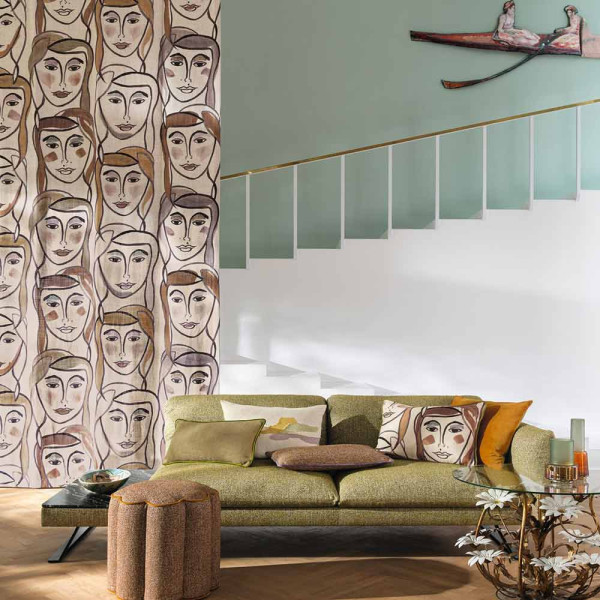 Bunte, abstrakte Gesichter und Linien sind auf dem hellen Dekostoff abgebildet. Der Stoff zeigt warme Farbtöne wie Orange, Rosa und Grün.