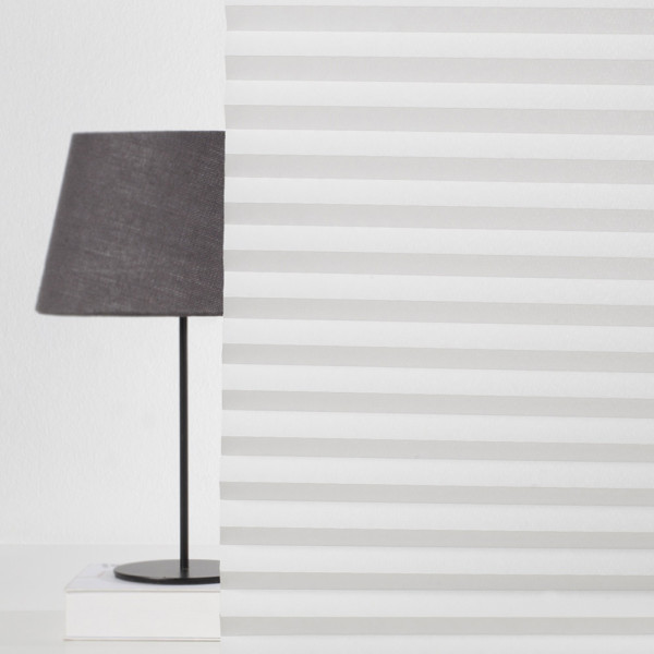 Weiße, gefaltete Plissees sind in gleichmäßigen Abständen angeordnet. Die Struktur hebt die halbtransparente Beschaffenheit des Materials hervor. Die Falten sind gleichmäßig und präzise gefaltet.