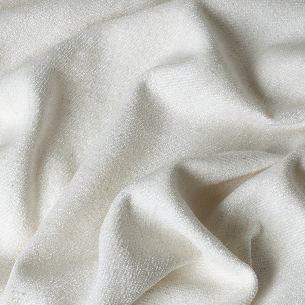 Hellbeiger Stoff mit feiner Struktur liegt zerknittert und unordentlich. Die Textur des Materials wirkt weich und leicht, ideal für Dekoration oder Vorhangstoffe.