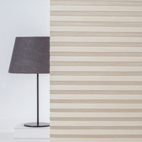 Beige Plissee mit wellenförmigem Muster liegt auf einem weißen Hintergrund. Die Falten sind gleichmäßig und verleihen dem Stoff eine elegante Textur.