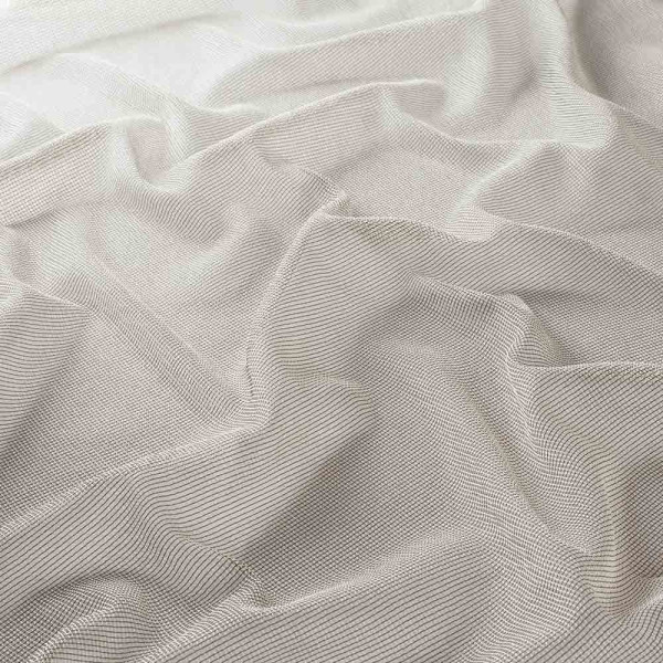 Taupefarbener, halbtransparenter Dekostoff mit feinem, geripptem Muster liegt verstreut auf einer Fläche. Der Stoff hat eine weiche Textur und fließt elegant.