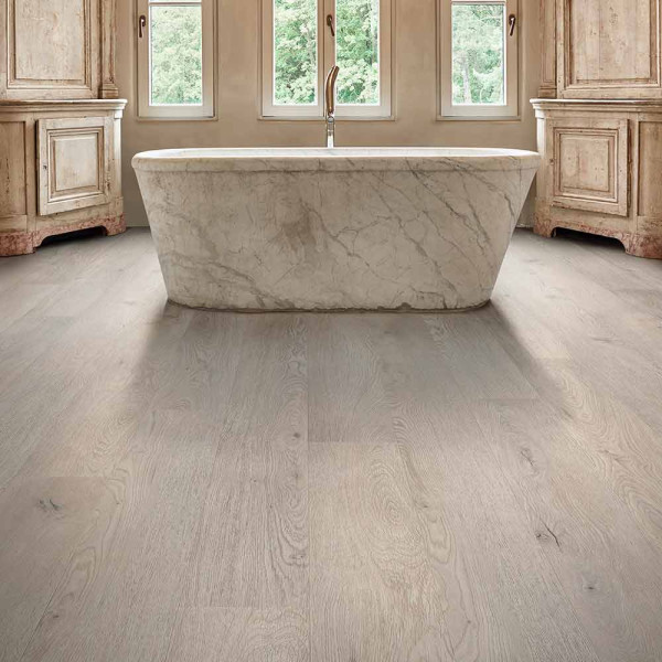 Helle, graue Holzoptik mit feinen Maserungen und Knoten, die den Charakter von natürlichem Holz imitiert. Der Bodenbelag vermittelt eine moderne und elegante Atmosphäre.