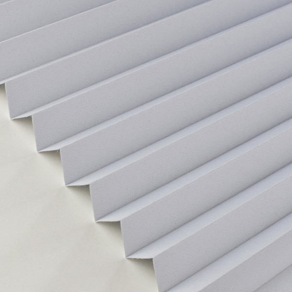 Plissee in Weiß mit strukturierter Oberfläche liegt gefaltet auf einem Untergrund. Es zeigt die verschiedenen Falten und die gleichmäßige Anordnung. Die Struktur ist gut sichtbar.