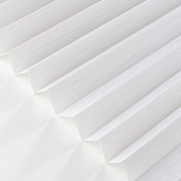 Weißes Plissee mit diagonal gefalteten Lamellen. Es zeigt eine gleichmäßige Struktur und lässt Licht durch, während es dennoch Sichtschutz bietet. Die Oberfläche wirkt elegant und schick.