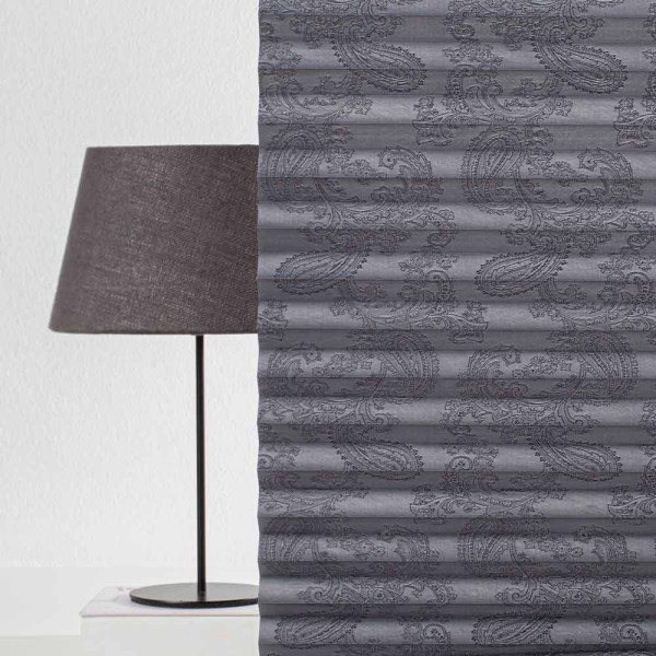 Dunkles Plissee mit elegantem Paisleymuster liegt gefaltet auf einer Oberfläche. Das Design bietet Sichtschutz und ist für maßgefertigte Fensterdekorationen geeignet.