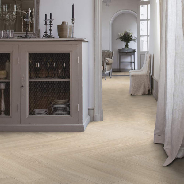 Helle, kreative Verlegeart eines Klebe-Vinylbodens mit einem hellen Holzdekor in Fischgrätenoptik. Die Oberfläche scheint glatt und stilvoll, ideal für moderne Innenräume.