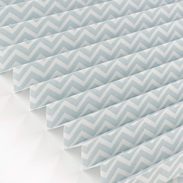 Plissee mit hellblauem, zigzagförmigem Muster liegt gefaltet auf einer flachen Oberfläche. Das Material wirkt halbtransparent und eignet sich für individuelle Fensterdecor.