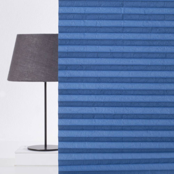 Blaue Plissees mit gefalteten Lamellen liegen ordentlich nebeneinander. Sie sind aus einem hochwertigen Material gefertigt und bieten Sichtschutz, ideal für Fensterdekorationen.