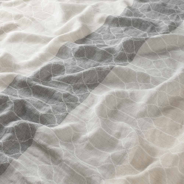 Halbtransparenter Vorhangstoff im Streifenmuster in Beige und Grau liegt gefaltet. Die Struktur des Stoffes zeigt sanfte Wellen und eine texturierte Oberfläche.