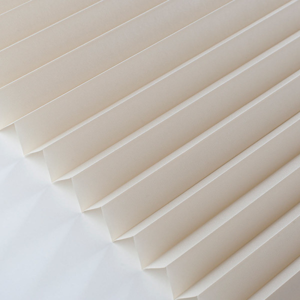 Hellbeige Plissee mit gefalteten Lamellen zeichnet sich durch eine halbtransparente Struktur aus. Es bietet eine elegante Lichtregulierung in Wohnräumen. Ideal für maßgeschneiderte Sonnenschutzlösungen.