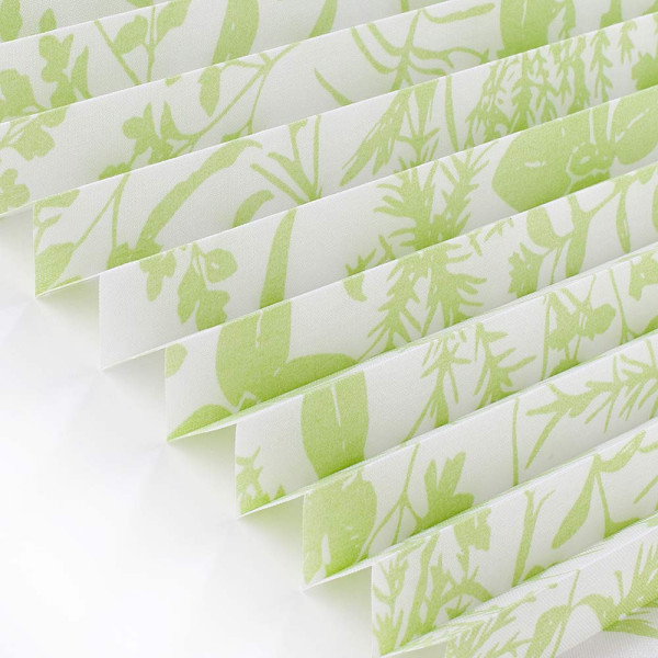 Hellgrünes, halbtransparentes Plissee mit Pflanzenmotiven in sanften Grüntönen liegt gefaltet auf einer weißen Oberfläche. Es wird zur Raumgestaltung und Lichtregulierung verwendet.