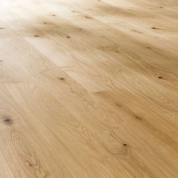 Hellbraunes Parkett mit Holzmaserung und kleinen Ästen ist gleichmäßig verlegt. Die Oberfläche wirkt vorgeölt und glänzend. Das Material eignet sich für Bodenbeläge in Wohnräumen.